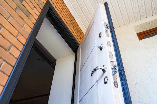 Open white metal front door with locks, bottom view on brick wall, close-up, security and privacy concept